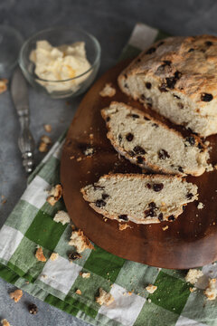 Irish Soda Bread Sliced on Cutting Board with Container of Butter and Butter Knife Beside Board