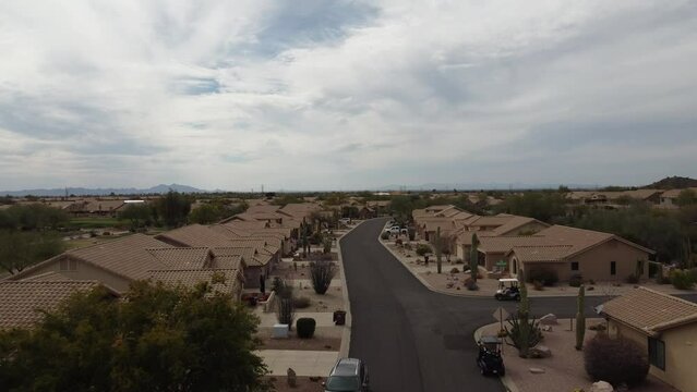 Aerial following shot of golf cart driving on a road in a desert retirement community
