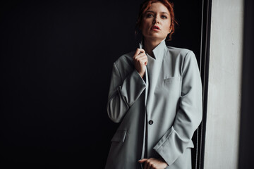 Portrait of candid authentic sexy redhead model girl posing in gray pantsuit with bra at studio
