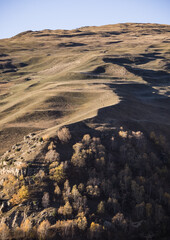 Fototapeta premium Mountain slope with rocks, cliffs and trees yellowed in autumn, birches, autumn early sunny morning