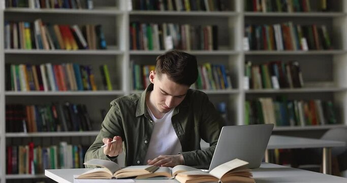 Serious College Student Guy Thinking On Project, Looking Away, Using Laptop In Library, Reading Open Books, Textbook, Writing Notes, Summary, Working On Research Study, Class Report