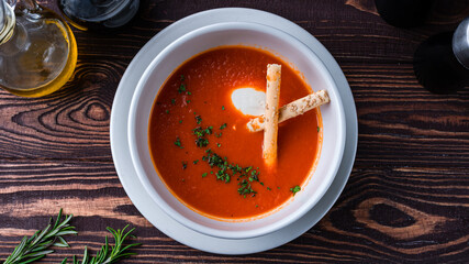 Lunch tomato soup puree with cream cheese, bread sticks and herbs.