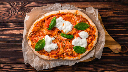 Italian food pizza with cheese, tomatoes, basil, tomato and cream sauce on a thick dough.