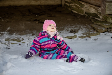 A little girl enjoys the sunny and cold winter wonderland of the north. The old log walls crackle from the frost.