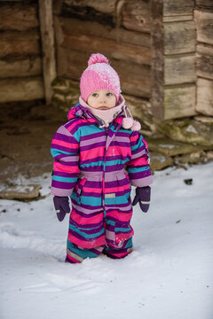 A little girl enjoys the sunny and cold winter wonderland of the north. The old log walls crackle from the frost.