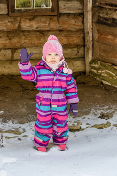 A little girl enjoys the sunny and cold winter wonderland of the north. The old log walls crackle from the frost.