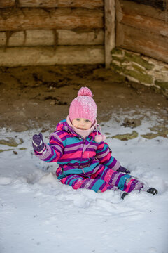 A little girl enjoys the sunny and cold winter wonderland of the north. The old log walls crackle from the frost.