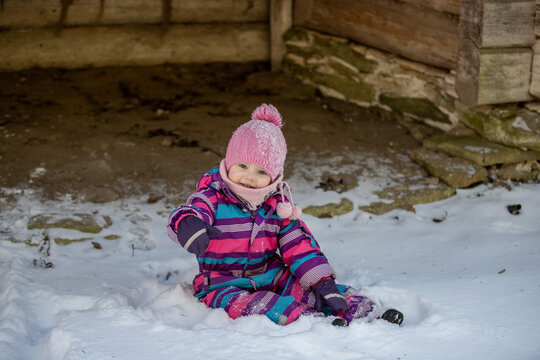 A little girl enjoys the sunny and cold winter wonderland of the north. The old log walls crackle from the frost.