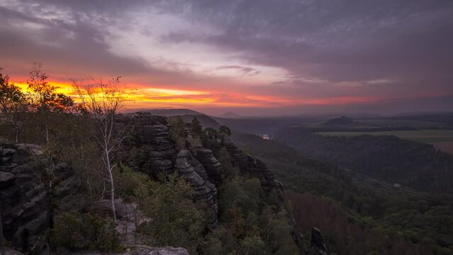 Sunrise Timelapse from Schrammsteine in autumn, Saxon Switzerland, Germany. In the distance you can see the river Elbe and the small village Schmilka.
