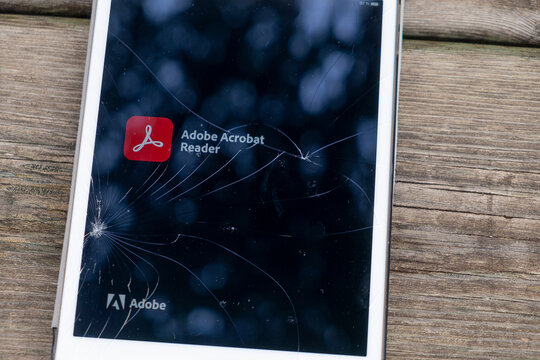 Madrid, Spain. 03-07-2023: Cracked screen of an ipad with the Adobe Acrobat Reader logotypo