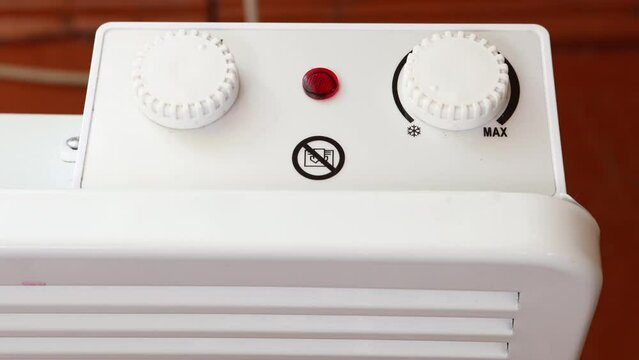 Setting thermostat of convector heater to minimum power by turning dial counterclockwise.