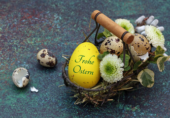 Frohe Ostern auf einem gelben Osterei in einem Korb mit Ostereiern, Wachteleiern und Blumen. 