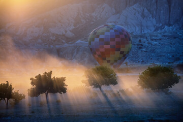 Balloon flight in Cappadocia mountains, Turkey. Contrasting silhouette of a tree in the rays of light