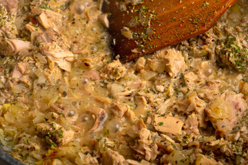 Cooking a side dish of meat in a pan, stirring with a wooden spatula