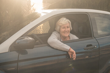 Happy senior woman inside her vehicle. Elderly woman feeling content while driving her vehicle