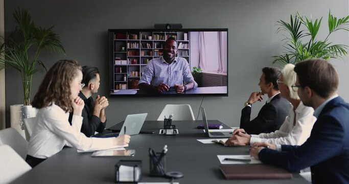 African man vacancy applicant passes job interview during group meeting with HR managers through video conference call, sit at desk in boardroom listen speech of business partner use modern technology