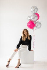 	
A woman with a pink balloon and a black shirt is sitting on a stool.