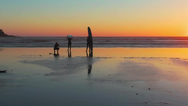 A drone shot of people silhouettes ready for surfing in Chesterman beach at sunset