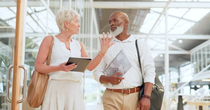 Elderly business people, tablet and walking in discussion for corporate strategy, planning or advertising at the office. Senior man and woman walk in conversation with touchscreen for marketing plan
