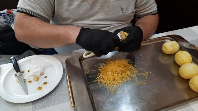 Male hands in black gloves remove the zest from a lemon with a special knife.
