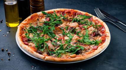 Italian pizza with chicken, bacon, sausages, mushrooms, cheese, tomato sauce and arugula.