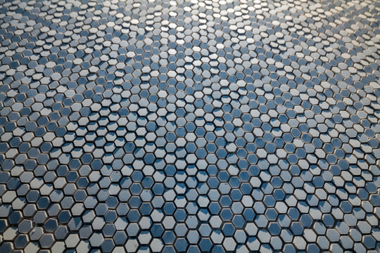 hexagonal extruded ceramic chips reflecting light and shadow, foreshortened view