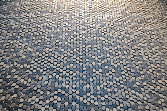 hexagonal extruded ceramic chips reflecting light and shadow, strong top light