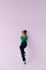 A beautiful glamorous girl with a slim figure in sunglasses in a blue jacket and green at a trendy hot stylish fashion photo shoot posing in a photo studio.