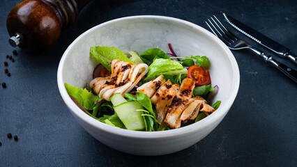 Fresh green salad with squid, cucumbers, lettuce, cherry tomatoes, arugula, beets and red onion.