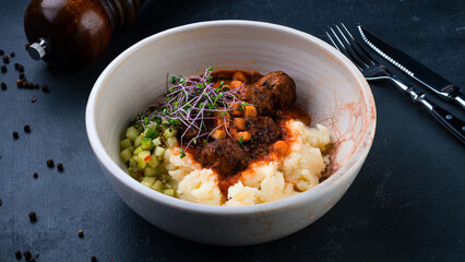 Fried beef meatballs with mashed potatoes, cucumber, mustard and microgreens.