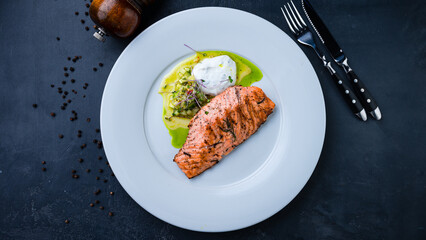 Salmon fillet with salad of cucumbers, microgreens and sauce.