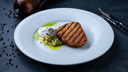 Fried pork fillet steak with salad of cucumbers, microgreens and sauce.