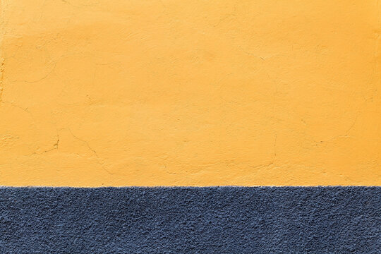 Colorful Mexican exterior wall painted in shades of Ukrainian flag colors and off CENTERED, distressed textures 