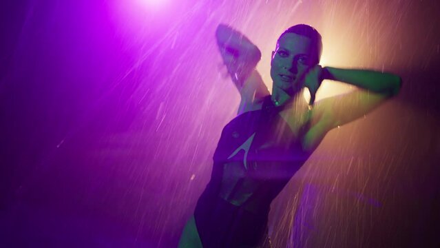 Sexy female stripper seducing client by erotic dance in private room of strip club. Cinematic close up slow motion shot on RED camera of woman with sensual hands touching wet body under water rain 4K