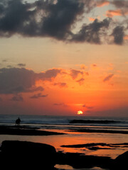 Sunset on the beach in pink tone. Sunset on the Uluwatu beach in a pink tone, with waves in the background and the coral reef appearing as silhouettes in the foreground.