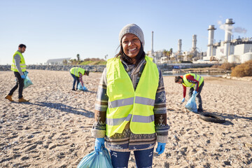 Young Latin activist looking camera holding garbage bag. Smiling woman standing with happy...