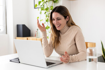 Happy young adult woman working on laptop computer from business office