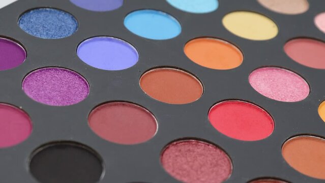 Close-up of a rotating colorful eyeshadow makeup palette featuring vibrant cosmetic shades