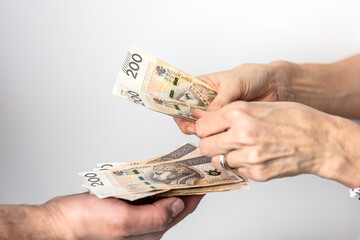 Dłonie mężczyzny i kobiety wymieniających się pieniędzmi. Banknoty na białym tle. Liczenie pieniędzy.