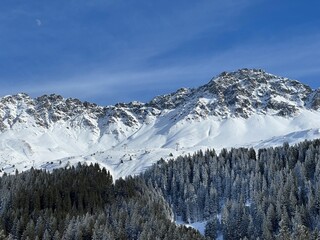 Beautiful sunlit and snow-capped alpine peaks above the Swiss tourist sports-recreational winter resorts of Valbella and Lenzerheide in the Swiss Alps - Canton of Grisons, Switzerland (Schweiz)