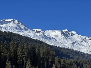 Beautiful sunlit and snow-capped alpine peaks above the Swiss tourist sports-recreational winter resorts of Valbella and Lenzerheide in the Swiss Alps - Canton of Grisons, Switzerland (Schweiz)