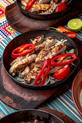 Traditional mexican food. Frying pan with hot pork, beef and chicken fajitas. Colorful Food Table Celebration Delicious Party Meal Concept. 