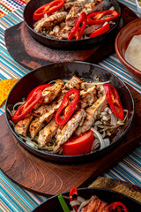 Traditional mexican food. Frying pan with hot pork, beef and chicken fajitas. Colorful Food Table Celebration Delicious Party Meal Concept. 
