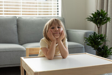 A cute little girl is sitting at the children's table in the living room