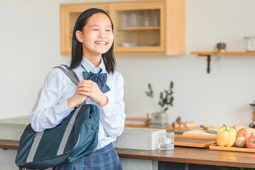 家のキッチンにいる制服を着た小学生・中学生・高校生の女の子
