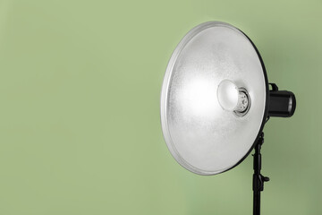 Professional beauty dish reflector on pale green background, space for text. Photography equipment