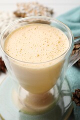 Glass cup with tasty eggnog on table, closeup