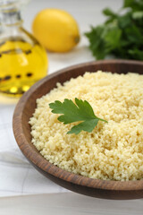 Tasty couscous with parsley on white wooden table, closeup