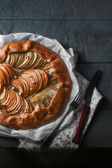 Delicious apple galette with walnuts, knife and fork on wooden table, flat lay