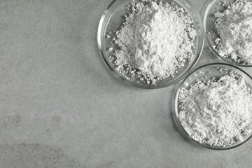Petri dishes with calcium carbonate powder on light grey table, flat lay. Space for text